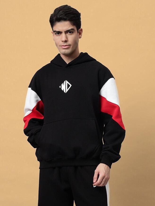 Man wearing a black BRIO fleece colorblock hoodie with red and white accents, featuring a front pocket and hood.