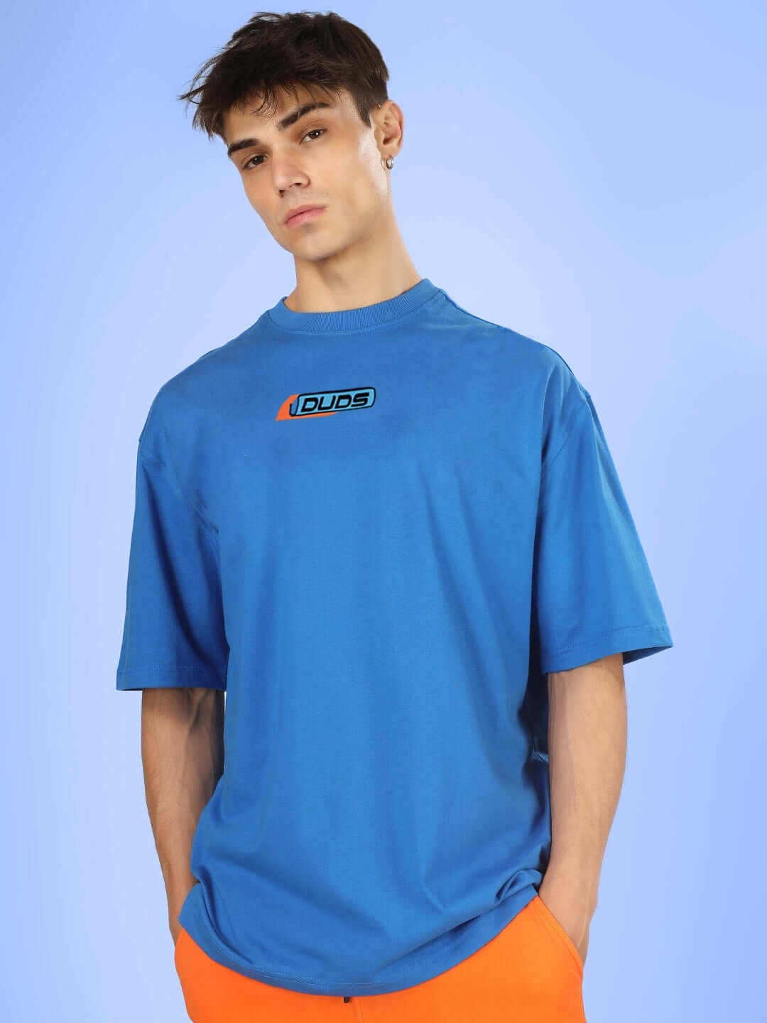 Male model wearing ROBO SHARK OVER-SIZED T-SHIRT ROYAL BLUE with a casual expression and vibrant background.