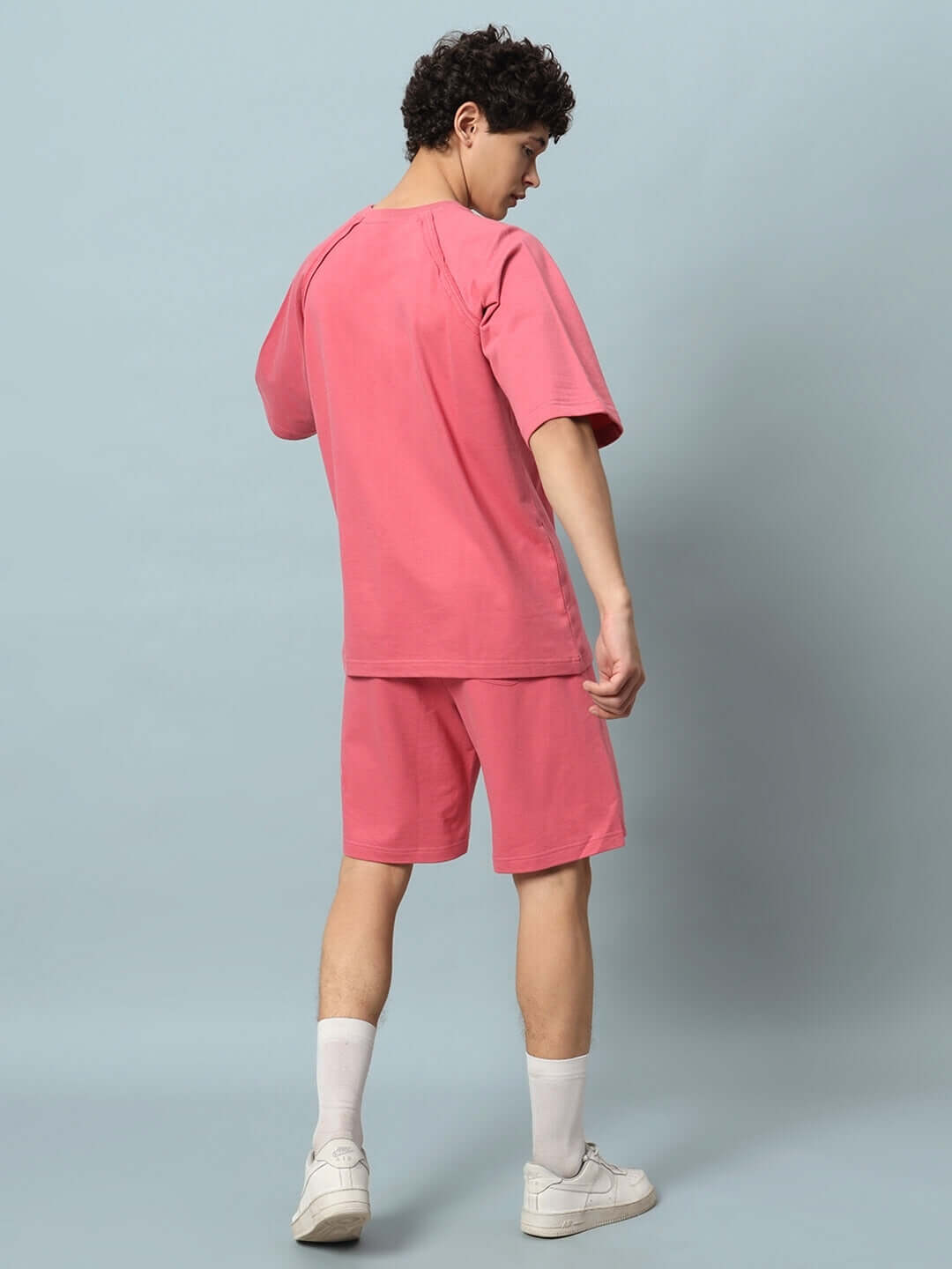 Man wearing COURAGE PRINT COTTON CO-ORD SET PINK in premium cotton fabric, side view showcasing shorts and t-shirt against light background.