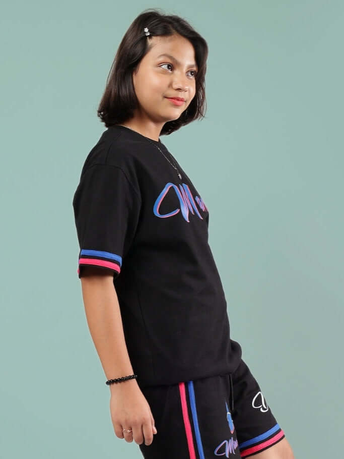 Child wearing a black oversized Miami t-shirt with multicolored accents, suitable for boys and girls by DUDS.
