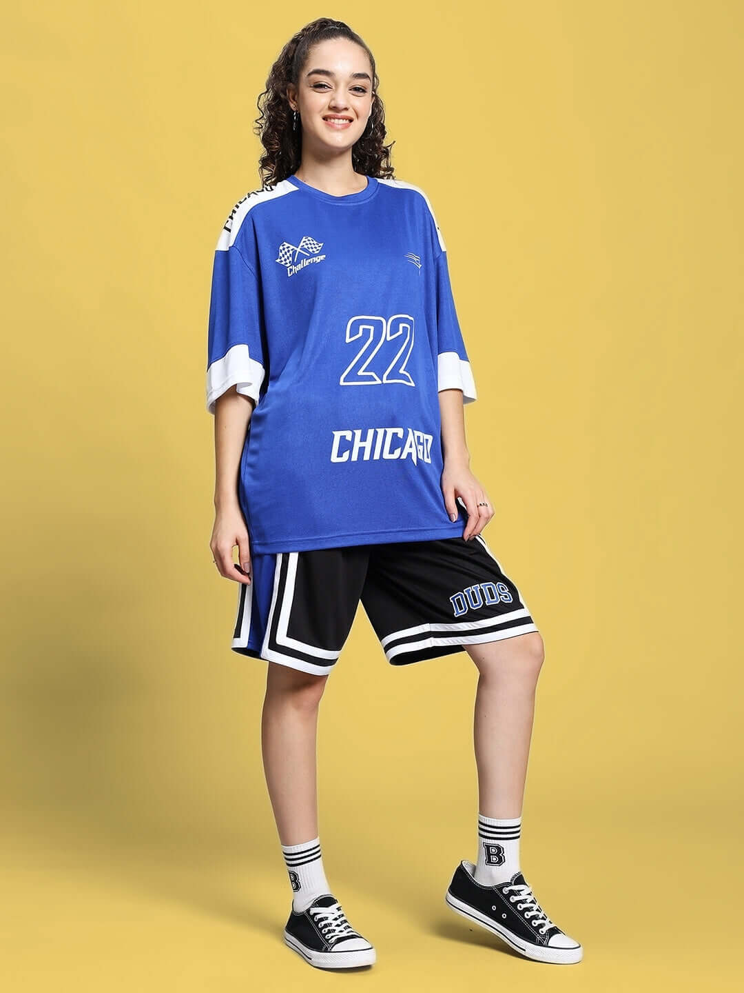 Woman wearing a royal blue women's challenge colorblock co-ord set with shorts, posing against a yellow background.