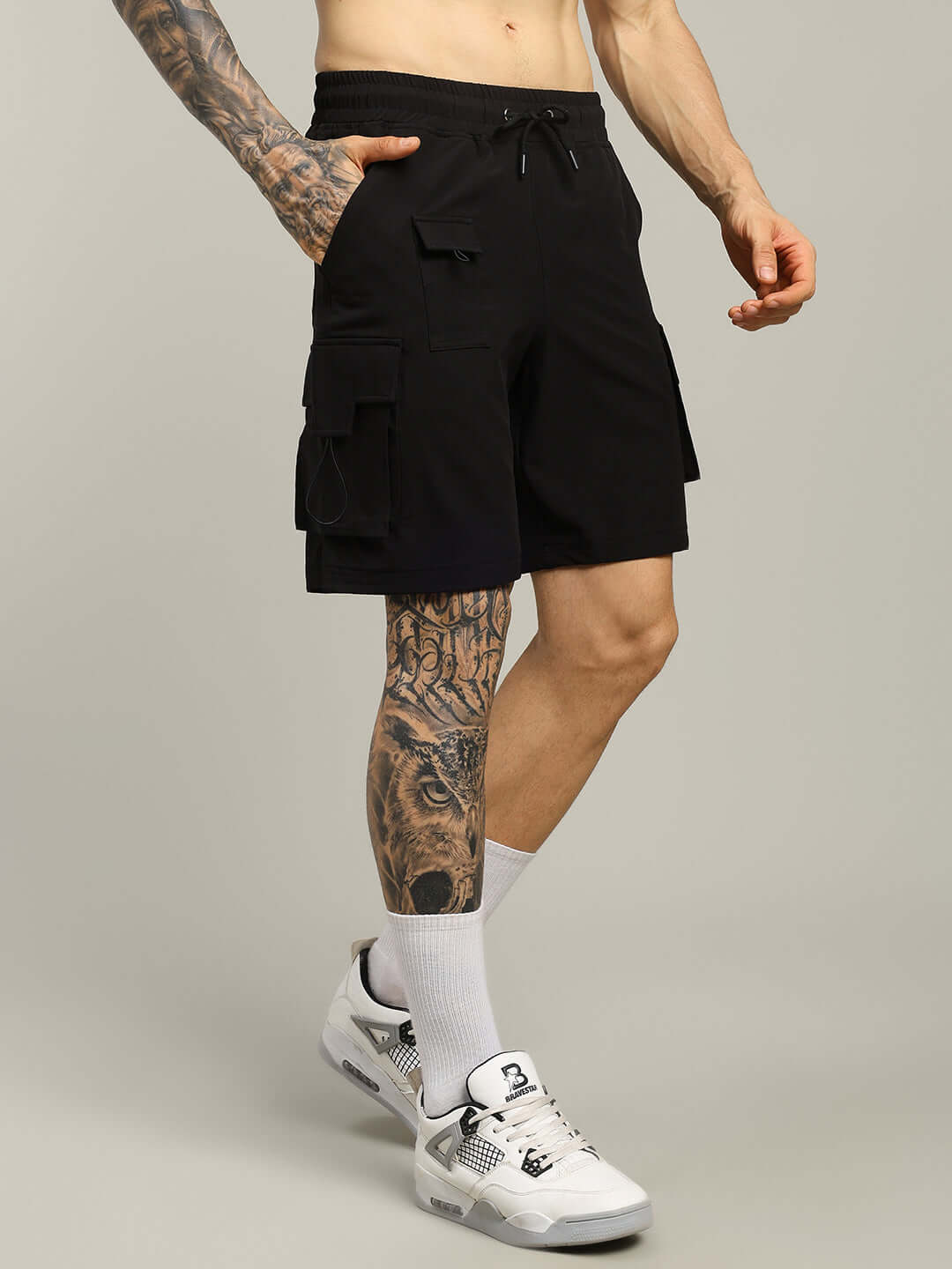 Black VEGA cargo shorts with side pockets, worn by a tattooed model; customizable size available. Ideal for casual wear.
