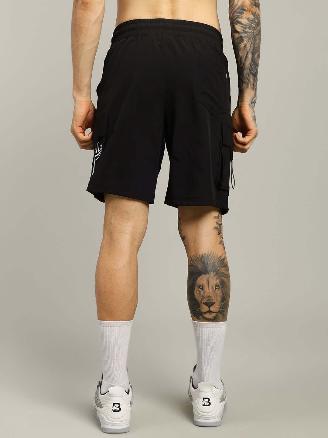 Back view of model wearing VEGA CARGO SHORTS in black with custom fit option, showcasing stylish and comfortable design.