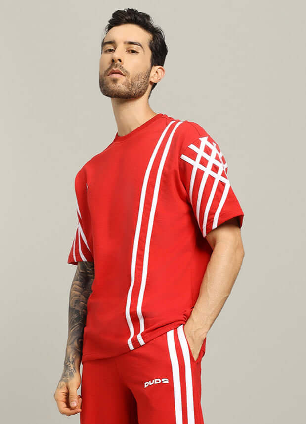 Man wearing a red United Stripe Over-sized T-shirt made from premium cotton and elastane, featuring white stripe design. Stylish casual wear.