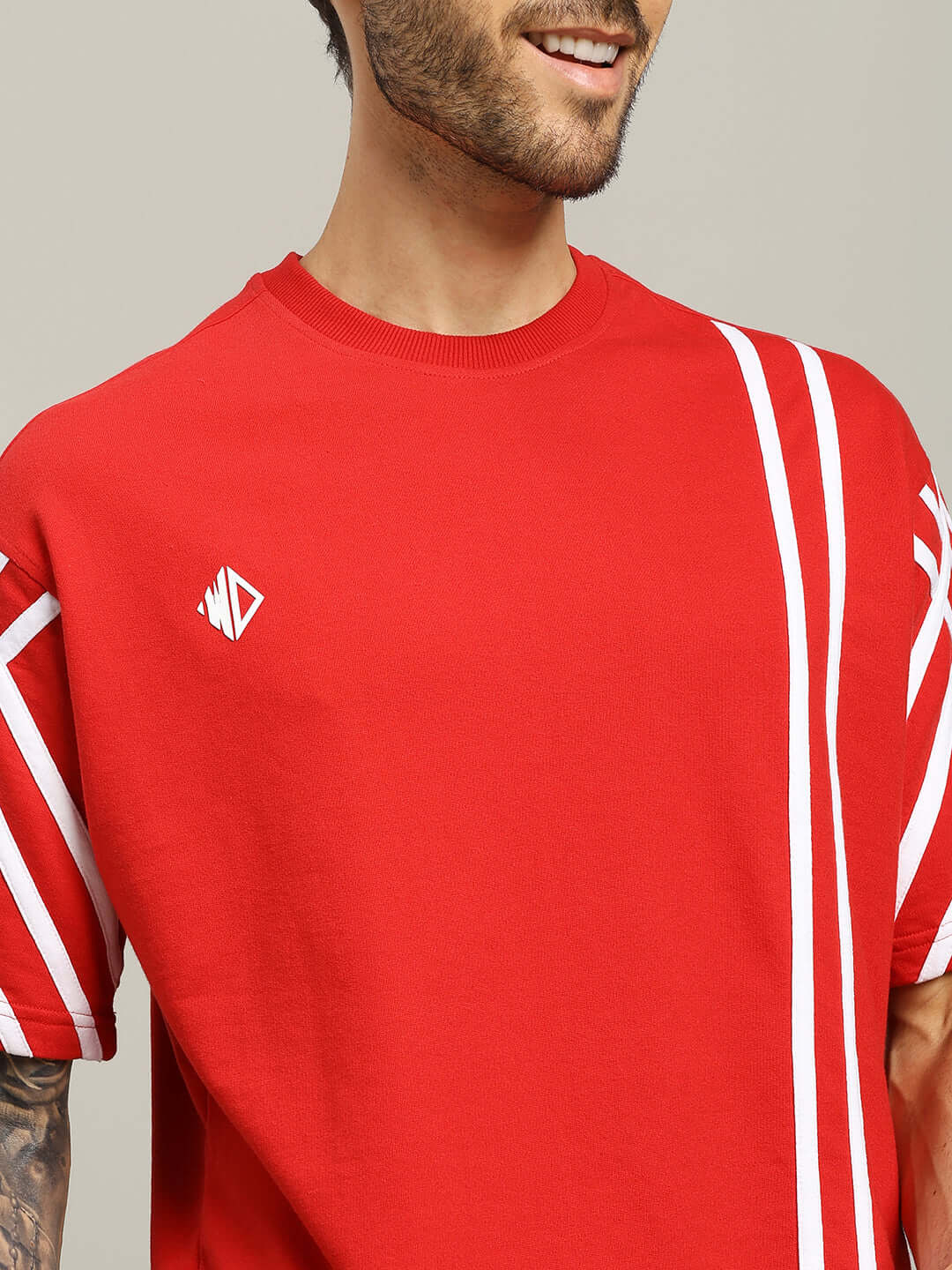 Red oversized t-shirt with white stripes, crafted from premium cotton, worn by a male model. Ideal casual wear.