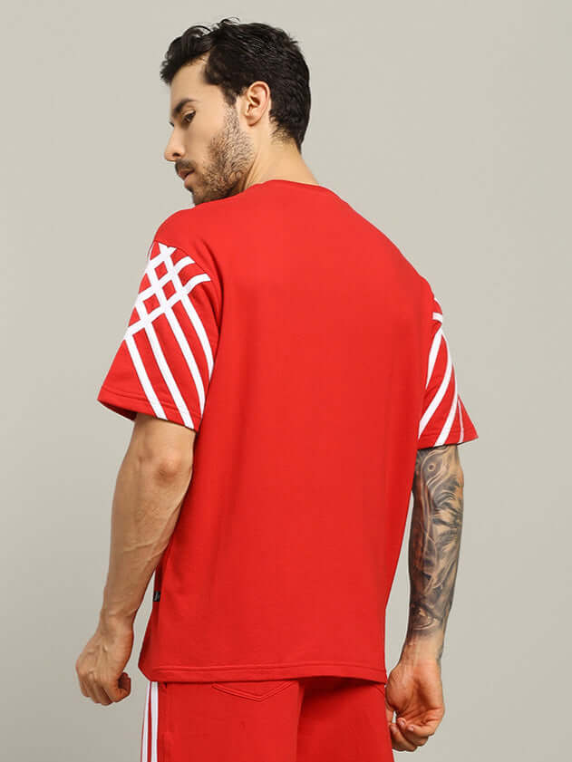 Man wearing red United Stripe oversized T-shirt with white stripes, made from premium cotton elastane blend.