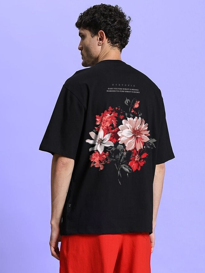 FLORAL PRINT OVERSIZED T-SHIRT BLACK with colorful floral design on back, worn by model against purple background.