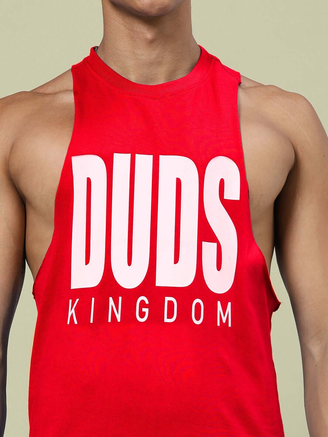 Close-up of DUDS KINGDOM red gym tank top with large white logo, showcasing a sleek, athletic fit on a male model.