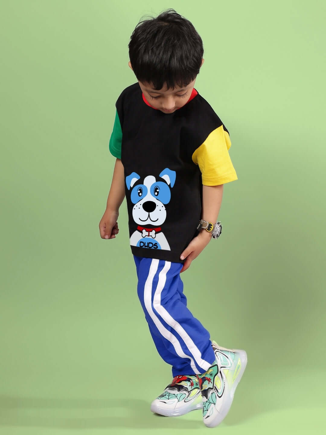 Child wearing a black and blue puppy dog printed outfit from DUDS, featuring colorful patches, perfect for boys and girls.