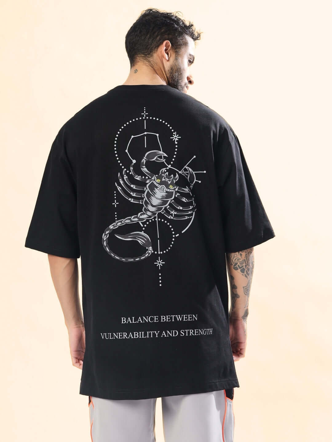 Back view of SCORPIO ZODIAC LONGLINE OVER-SIZED T-SHIRT BLACK with scorpion graphic and text "Balance between vulnerability and strength."
