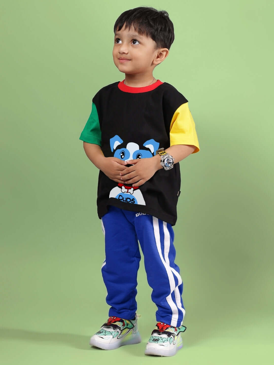 Child wearing a black and blue puppy dog printed co-ord set, featuring colorful sleeves and striped pants, by DUDS.