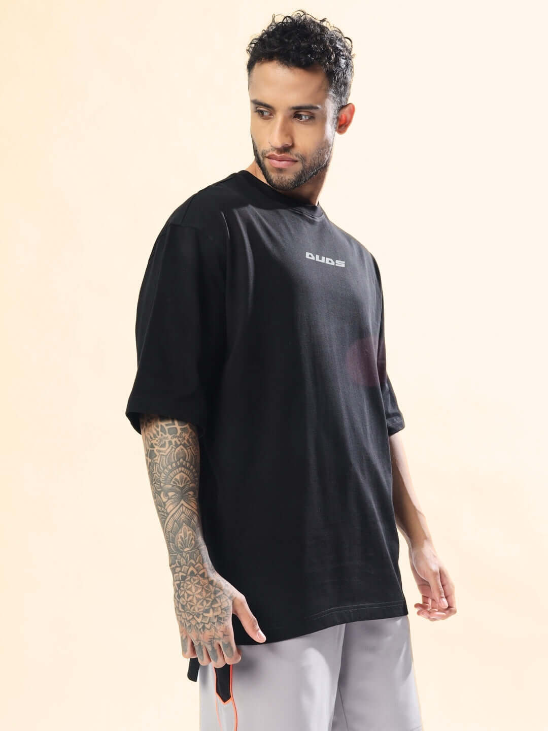 SCORPIO ZODIAC LONGLINE OVER-SIZED T-SHIRT BLACK modeled by a person with tattooed sleeve, featuring casual style against a light background.