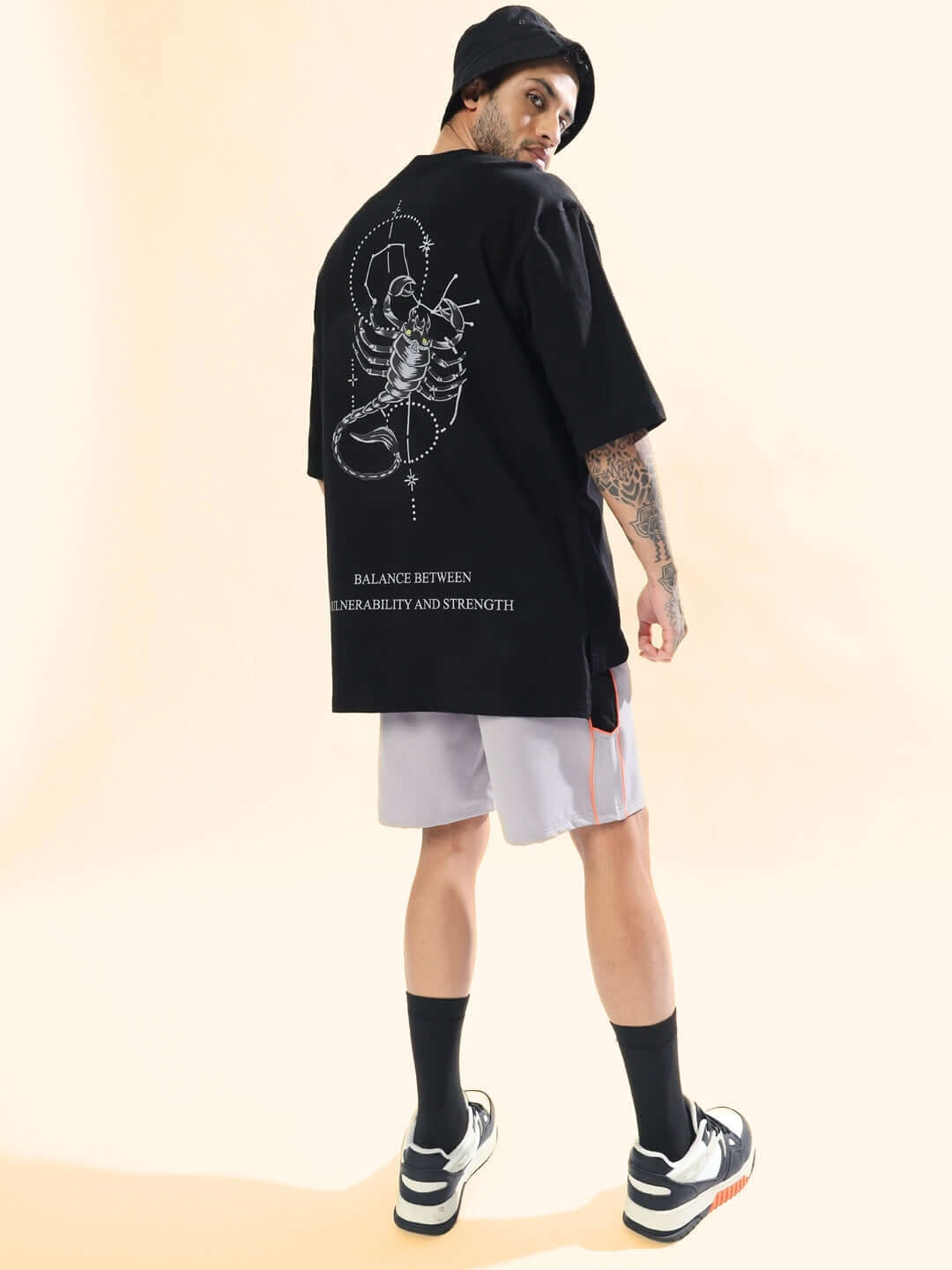 Man wearing SCORPIO ZODIAC LONGLINE OVER-SIZED T-SHIRT BLACK with scorpion graphic on back. Casual streetwear fashion look.