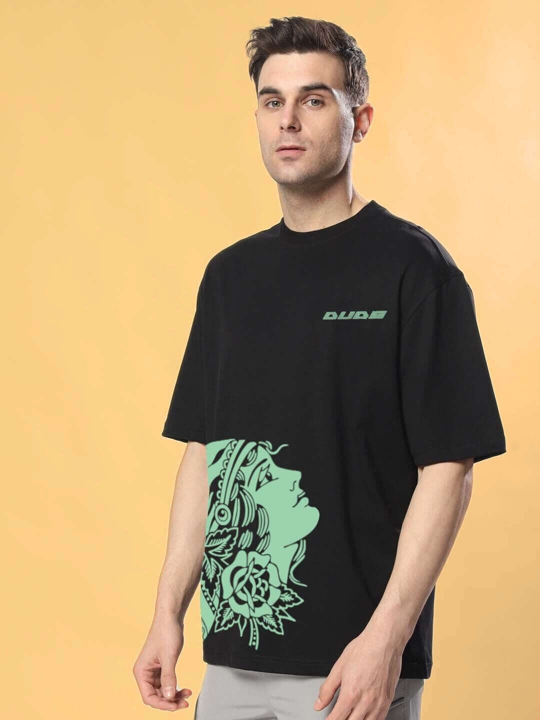 Model wearing KINNAUR OVER-SIZED T-SHIRT BLACK with unique graphic design by DUDS, available for custom fit.