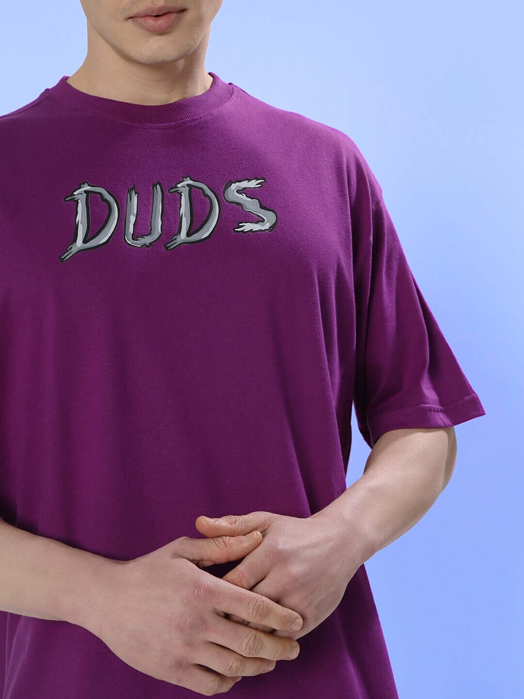 Person wearing POSITIVE RABBIT OVER-SIZED T-SHIRT PURPLE with "DUDS" text in stylish font.