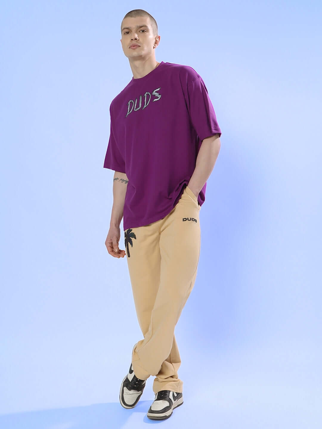 Model wearing POSITIVE RABBIT OVER-SIZED T-SHIRT PURPLE with tan pants, displaying urban streetwear style.