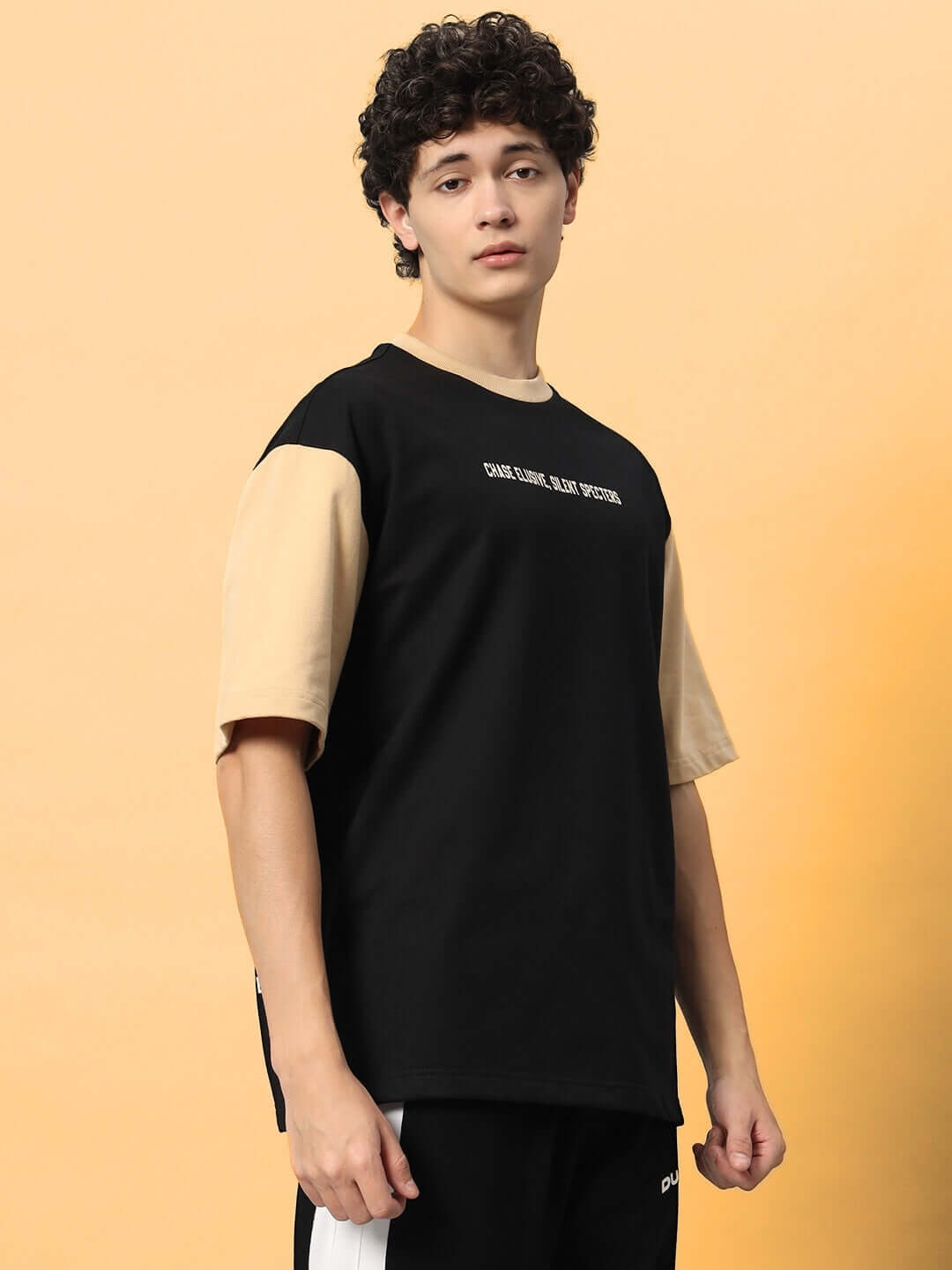 Model wearing PHANTOM OVER-SIZED T-SHIRT BLACK BEIGE with black base and beige sleeves showcasing bold streetwear style.