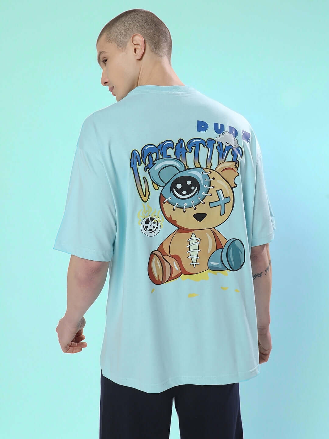 Man wearing DUDS CREATIVE OVER-SIZED T-SHIRT SKY BLUE with creative cartoon design on back.