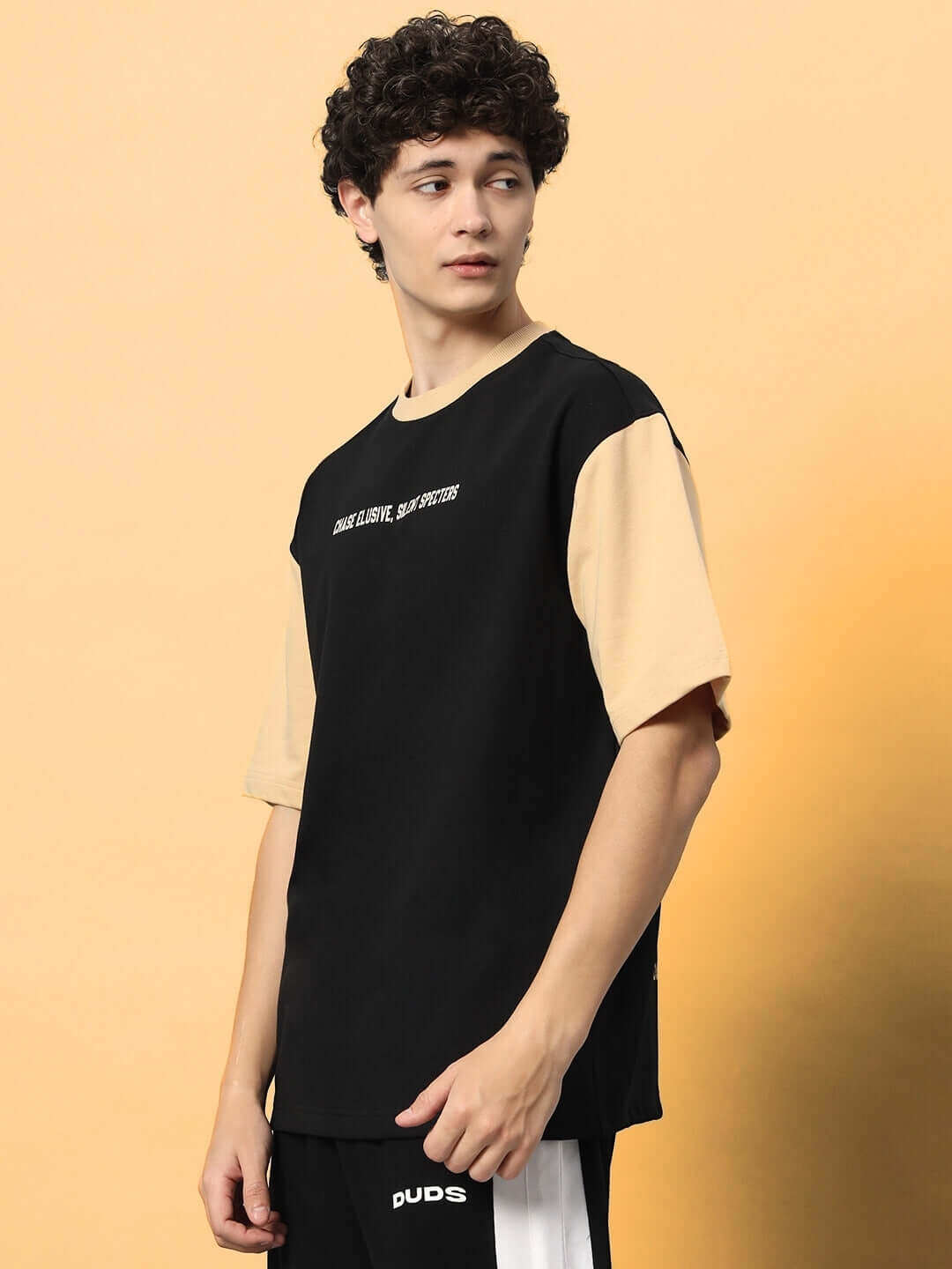 Model wearing PHANTOM OVER-SIZED T-SHIRT BLACK BEIGE with black body and beige sleeves, showcasing modern streetwear fashion.