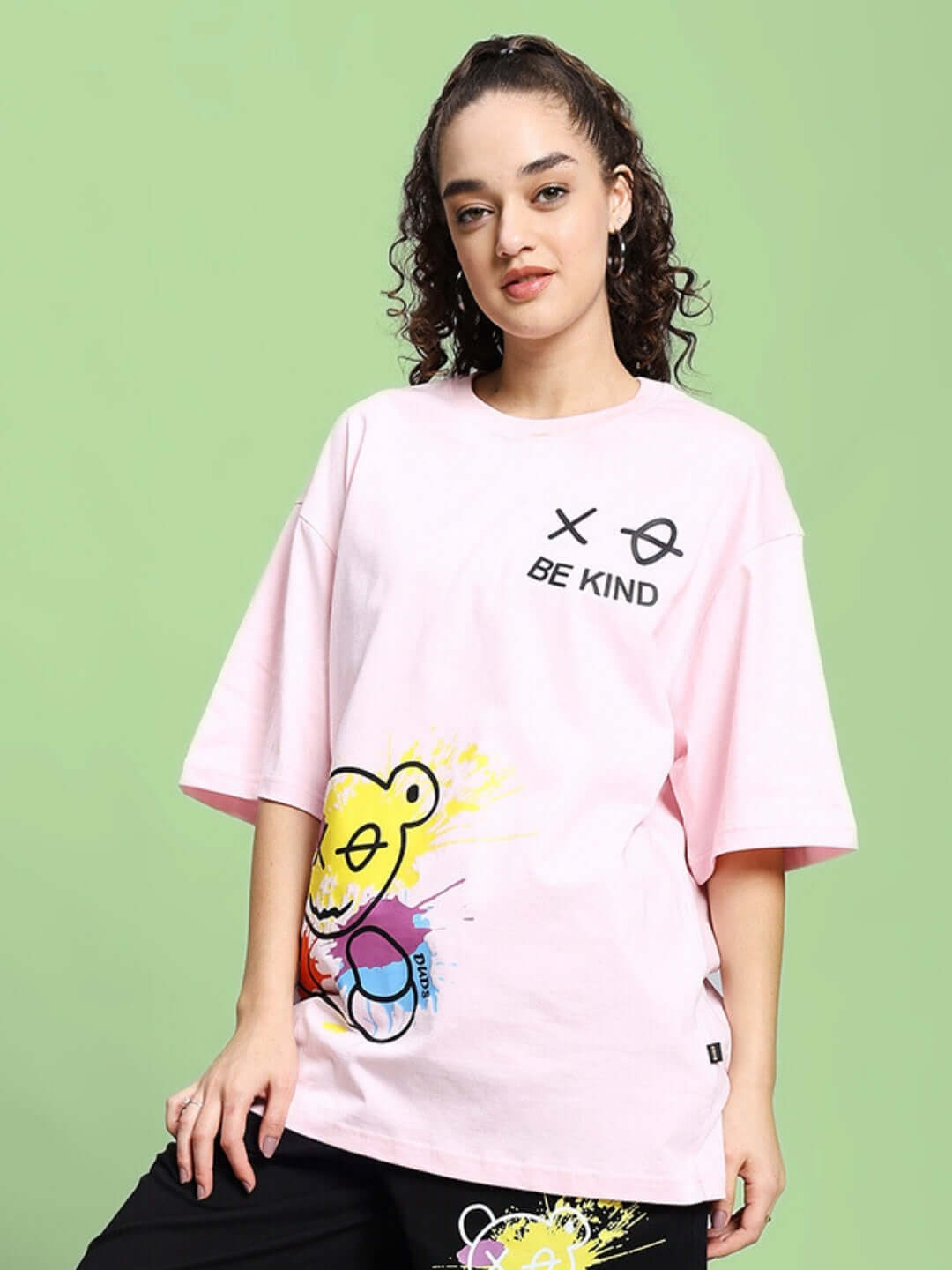 Model wearing Women's Be Kind Over-Sized T-Shirt in pink with graphic print, made from premium cotton blended fabric, bio-washed for softness.
