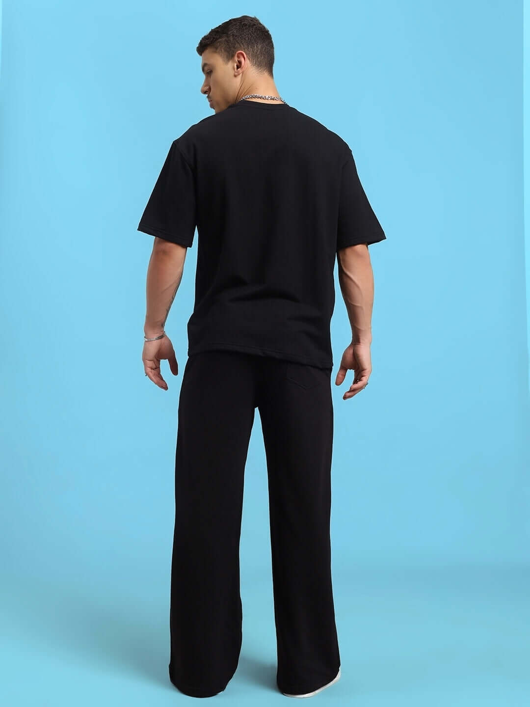 Model wearing Hollister black tie-dye co-ord set, back view with short sleeves and pants made of premium cotton fabric, on blue background.