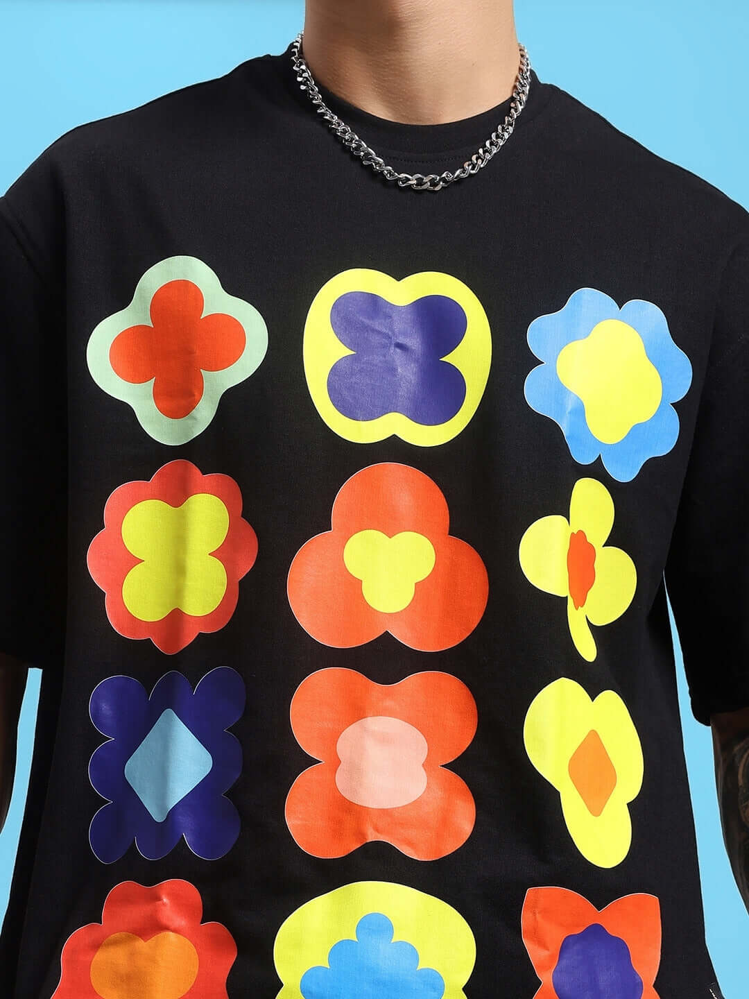 Man wearing black T-shirt with colorful abstract flower patterns, blue background