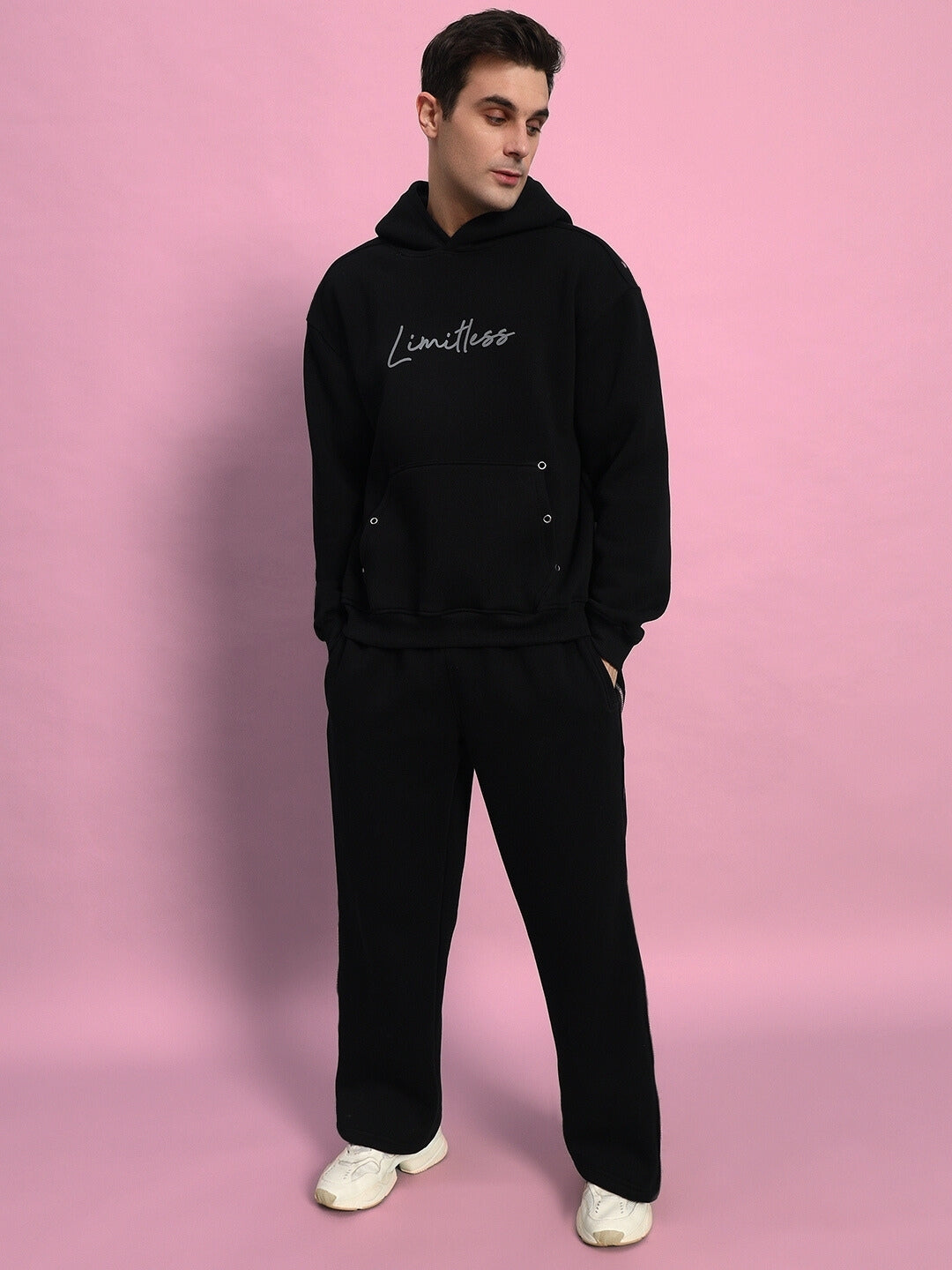Person wearing black LIMITLESS FLEECE REFLECTOR CO-ORD against pink background, featuring reflective design, comfortable fit.