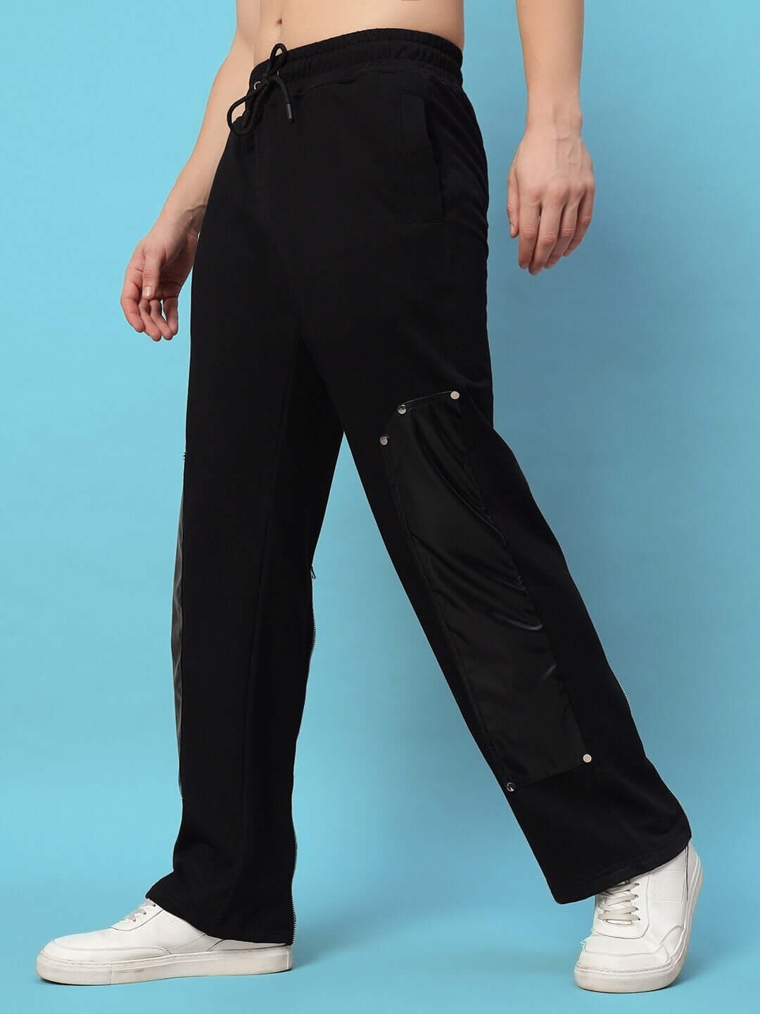 "Black joggers with leather patch detail, shown in a stylish side view on a blue background, showcasing comfortable fit and modern design."