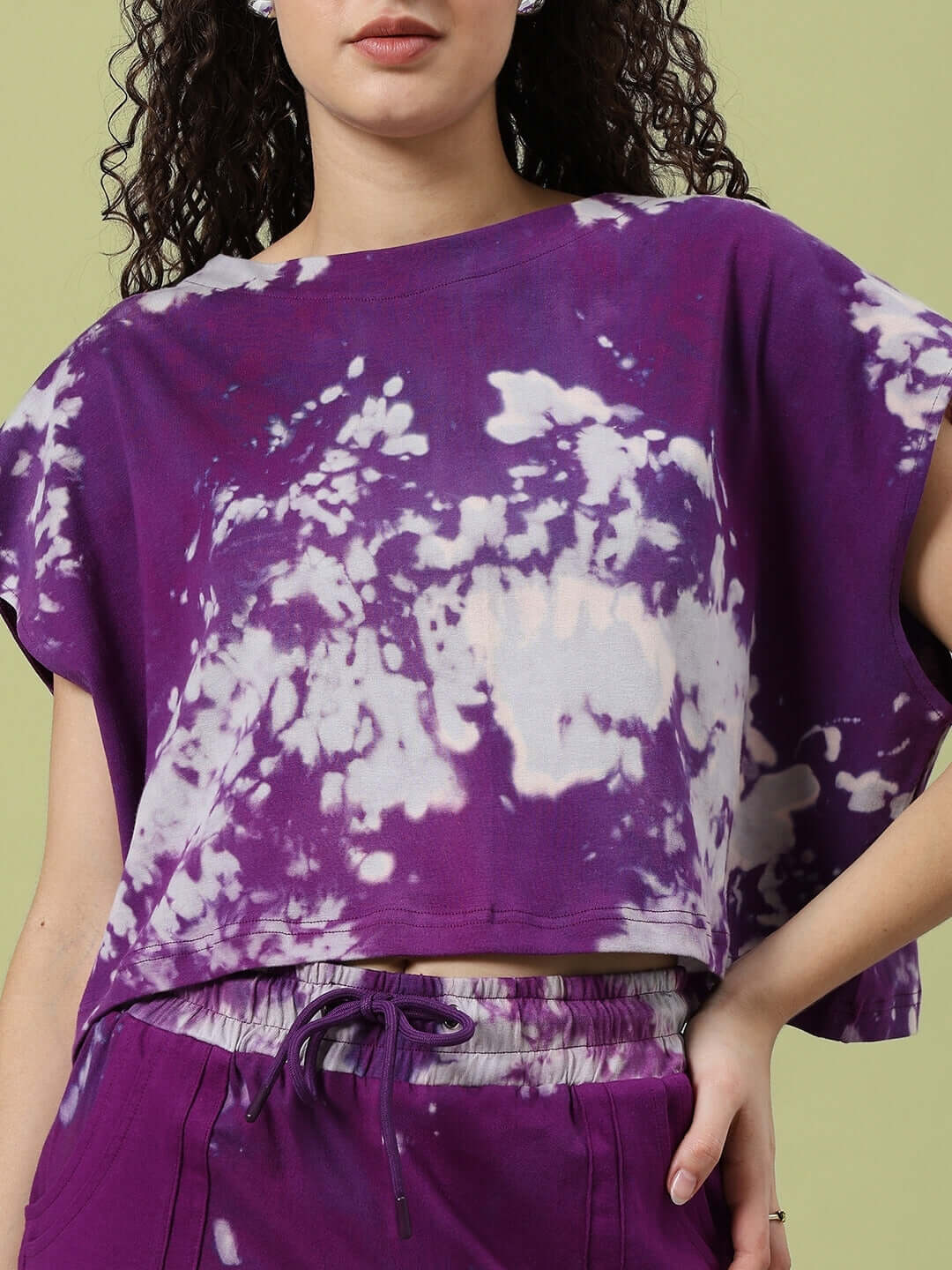 Woman wearing a purple tie-dye co-ord set made of cotton French Terry, featuring a short-sleeved top and drawstring pants.