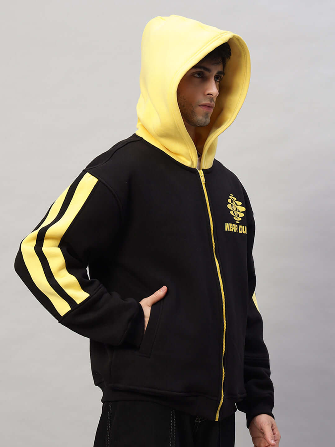 Black and yellow colorblock hoodie with zipper, featuring a hood, striped sleeves, and logo on chest, modeled in profile.