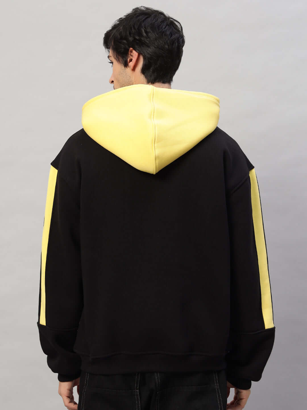 Back view of a Cruiser Fleece Colorblock Hoodie in black and yellow, featuring a stylish design with contrasting hood and sleeve accents.