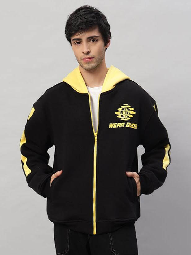 Model wearing Cruiser Fleece Colorblock Hoodie in black-yellow with front pockets and logo print. Casual and stylish outerwear.