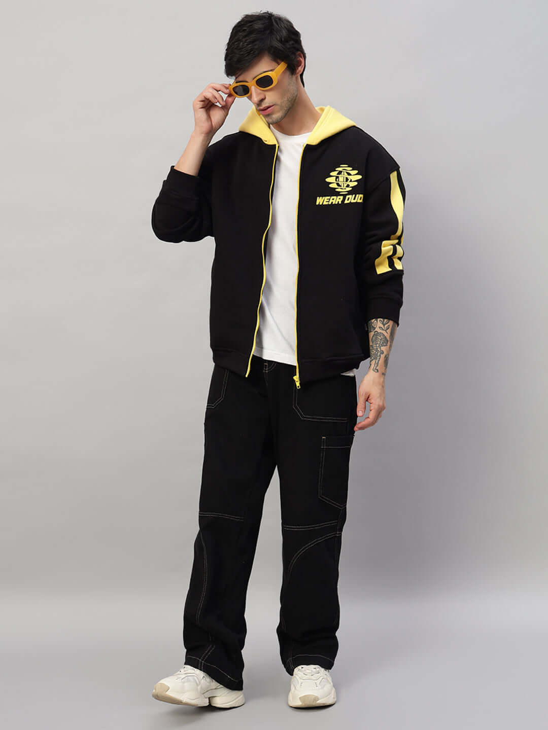 Model wearing Cruiser Fleece Colorblock Hoodie in black and yellow, paired with black pants and yellow sunglasses.