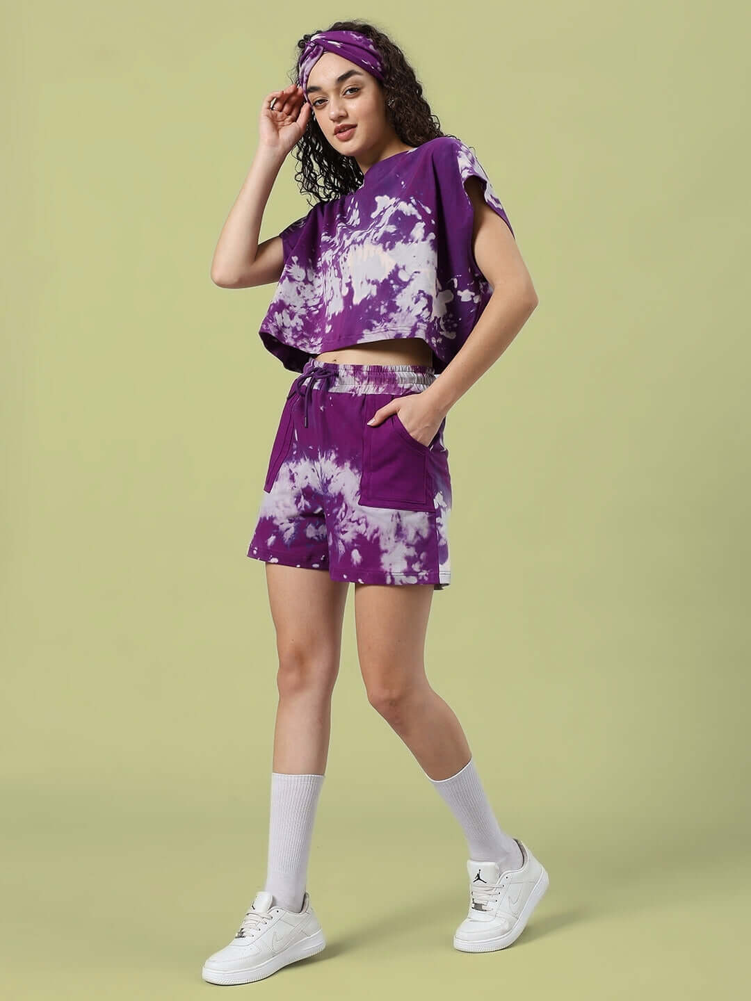Model wearing Women's Jambul Tie-Dye Co-ord Set in purple, featuring premium cotton fabric, short sleeves, and elastic waistband, with white sneakers.