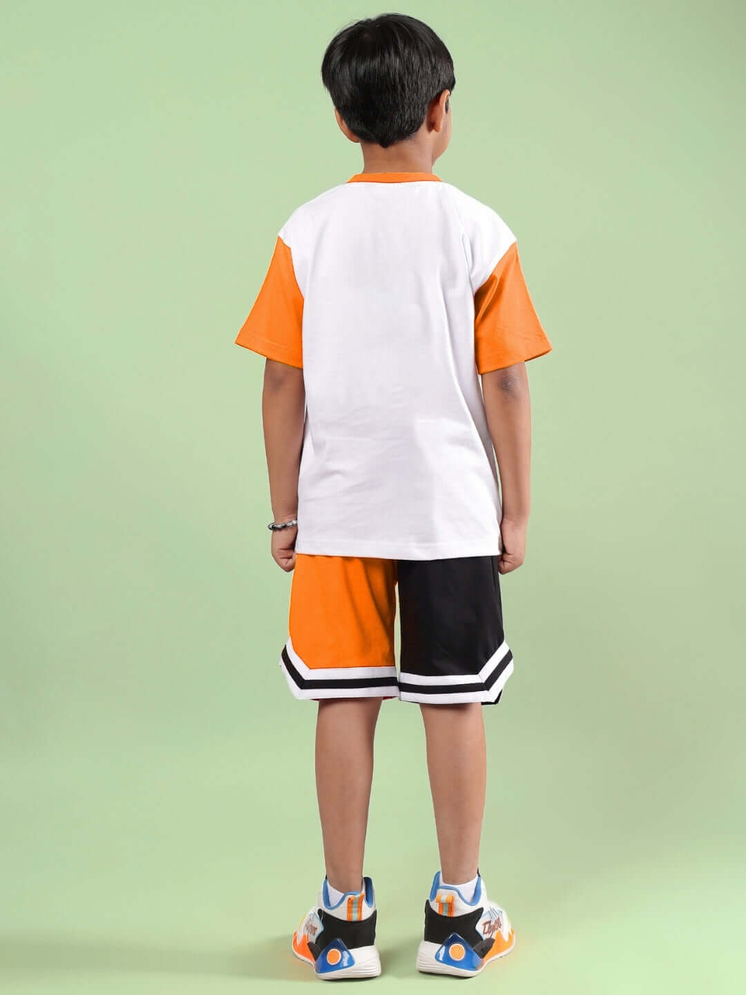 Boy wearing a white and orange Friendship Bucket Co-ord set from DUDS, showcasing rear view. Ideal for boys and girls, made to order.