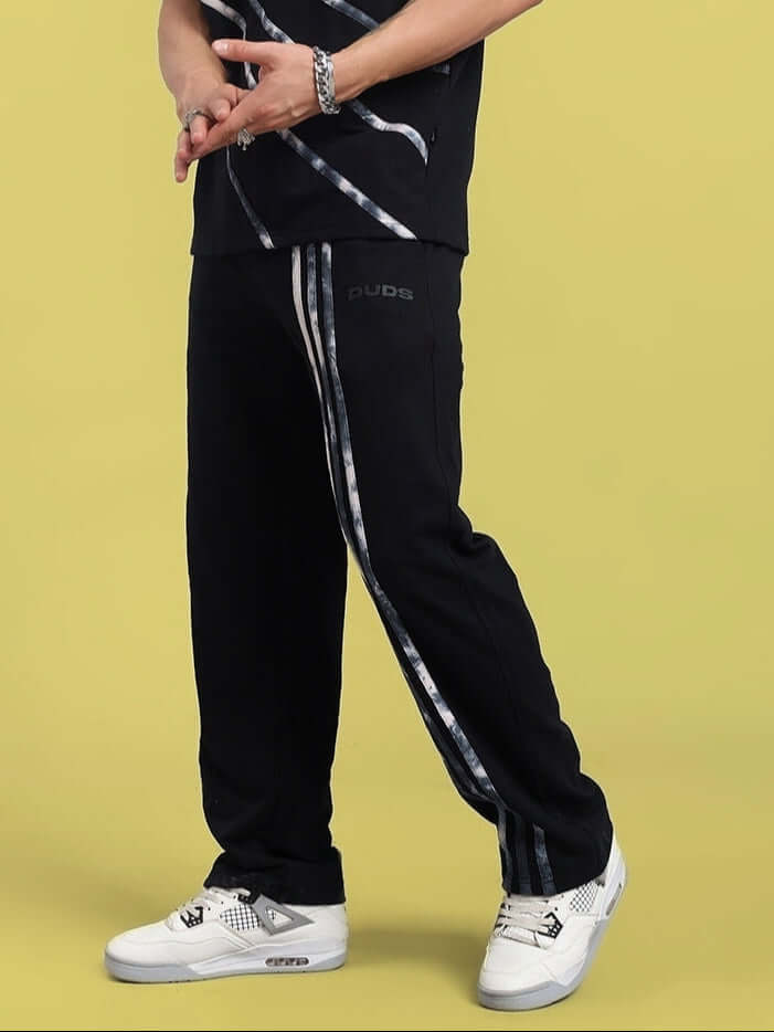 Man wearing FLICKER JOGGER in black, showcasing the stylish design by DUDS with stripe details, paired with white sneakers.