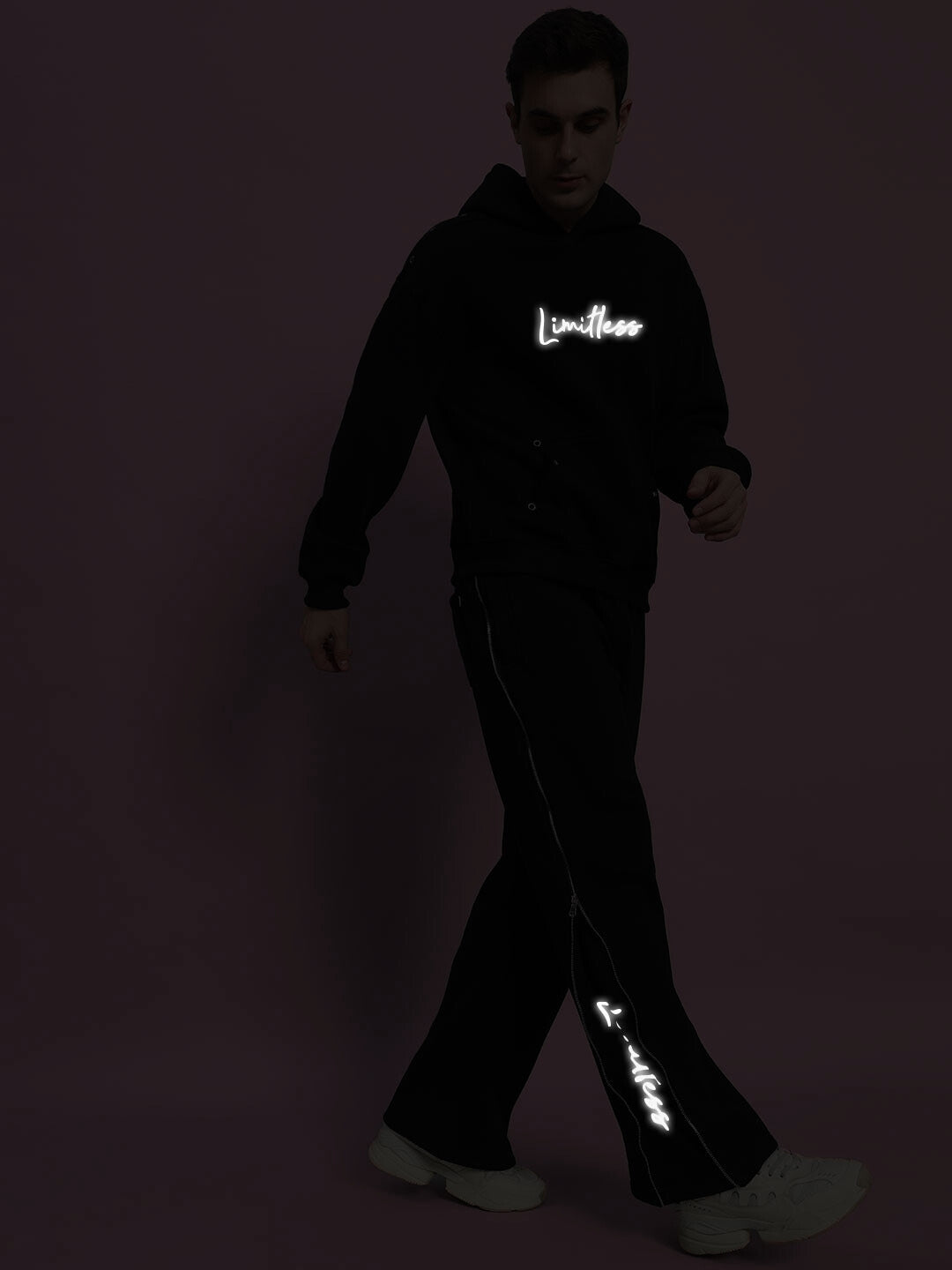 Man wearing Limitless Fleece Reflector Co-Ord in black with glowing logo, showcasing comfortable and stylish reflective fashion.