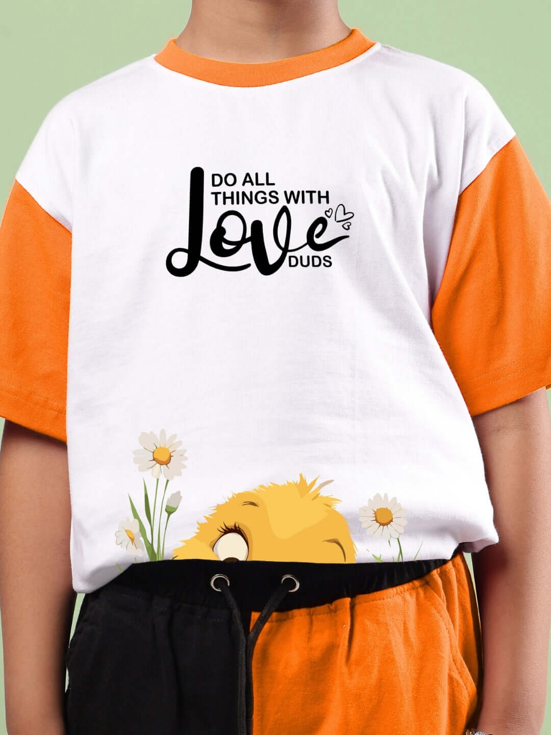 Child wearing Friendship Bucket Co-ord in white and orange with 'Do All Things with Love DUDS' print, floral and playful design.