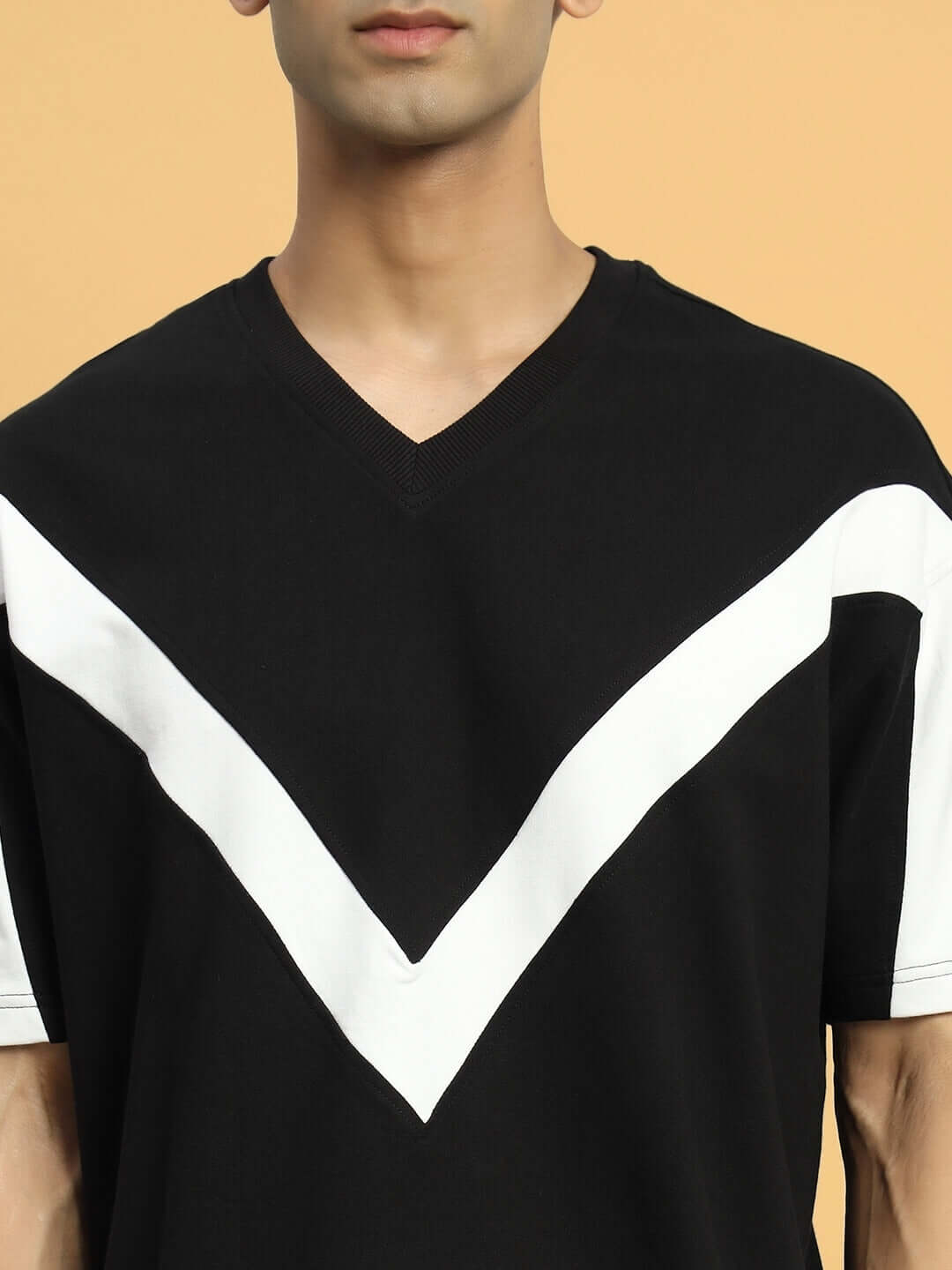Model wearing black ADROIT oversized T-shirt with white V-stripe, made of premium heavy gauge fabric cotton blend.