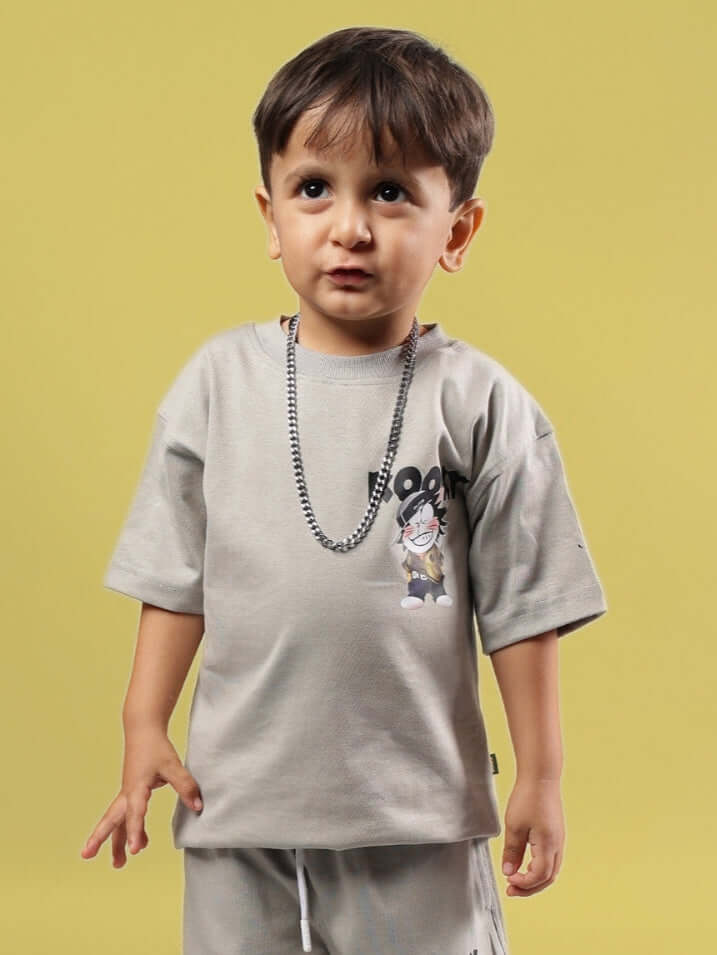 Young child wearing KOOKY grey t-shirt suitable for boys and girls, with cartoon character print, against a yellow background.