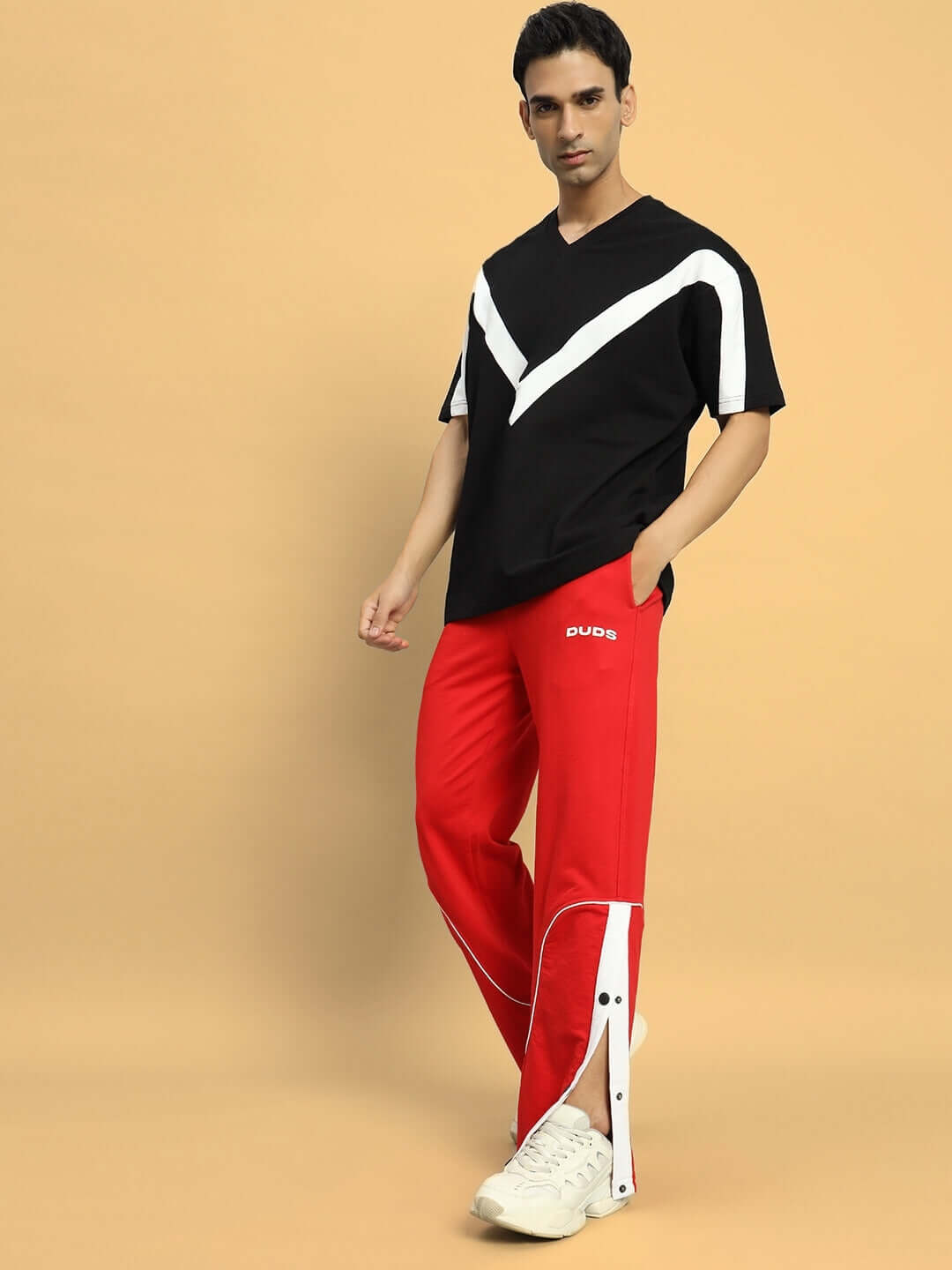 Model wearing black ADROIT over-sized T-shirt with premium cotton blend. Comfortable fit, styled with red pants, perfect for casual wear.