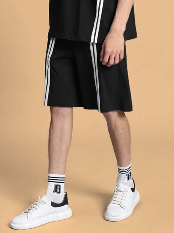 Model wearing black Outlook Regular Fit Shorts with white sneakers and socks featuring stripes, showcasing casual style.