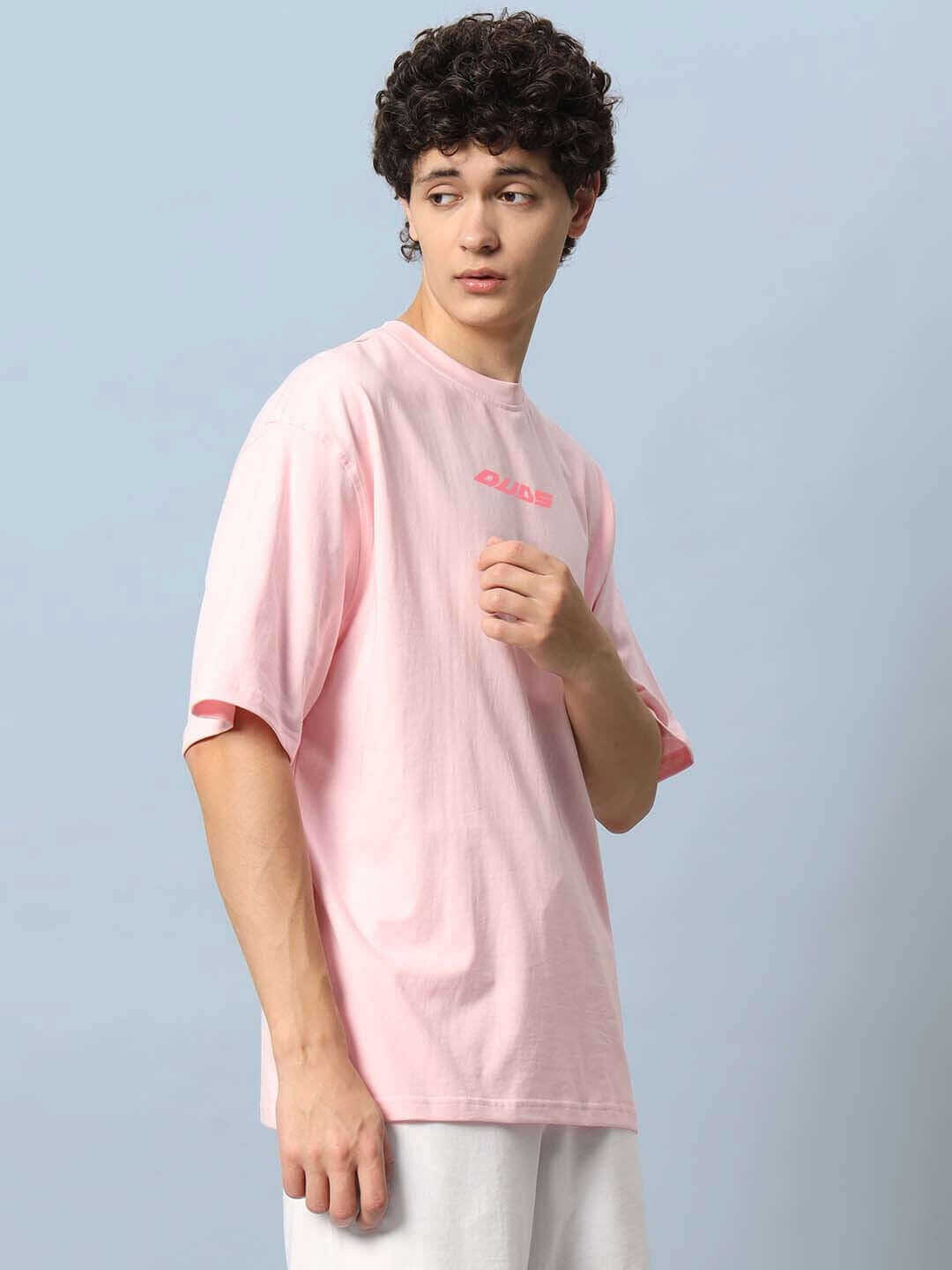 Man wearing DYING GOD OVER-SIZED T-SHIRT PINK with soft fabric, styled casually, showcasing the relaxed fit of this trendy t-shirt for fashion enthusiasts.