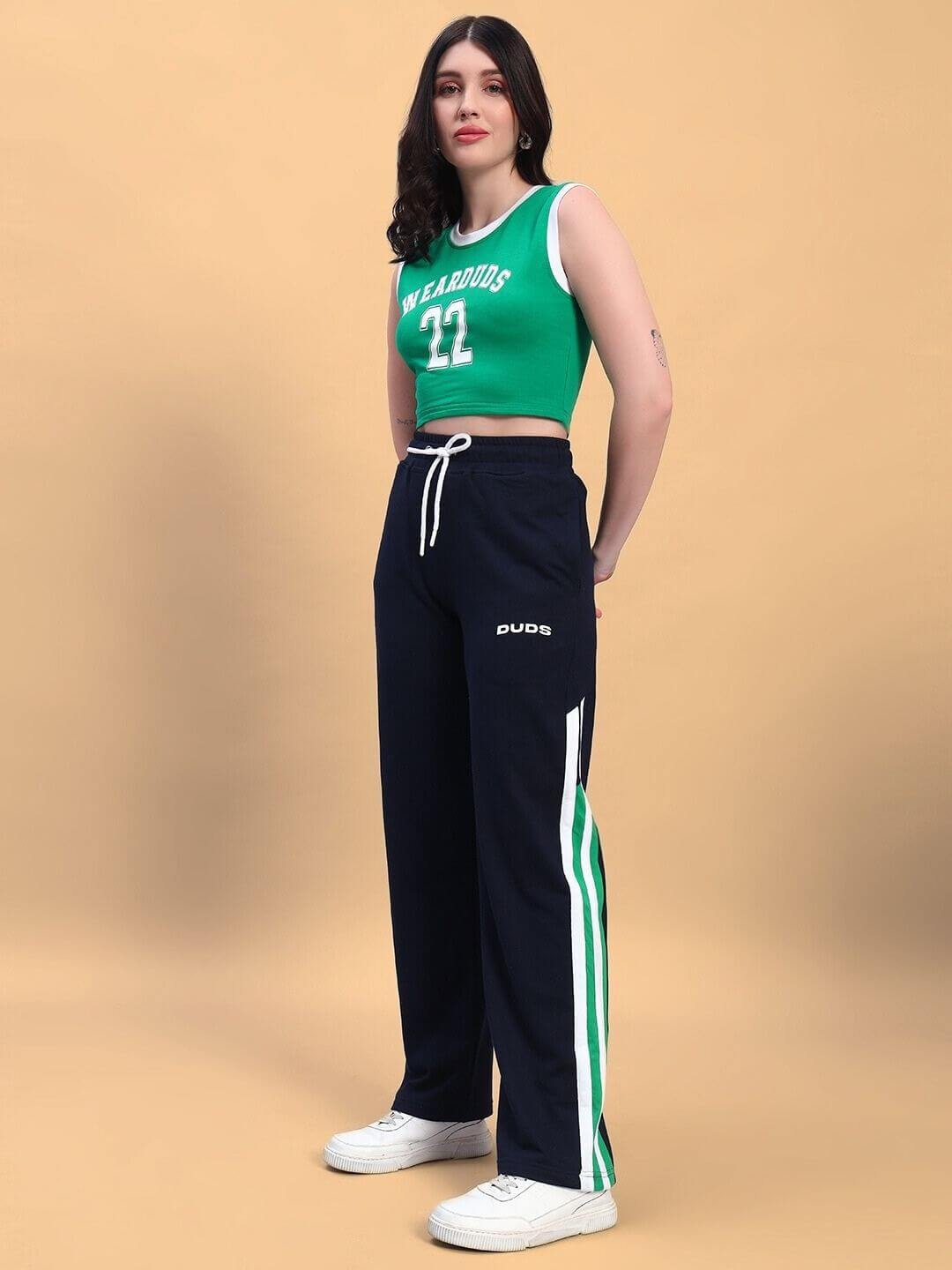 Woman wearing a green and navy women's player co-ord set, featuring a green top and navy pants with white and green stripes.