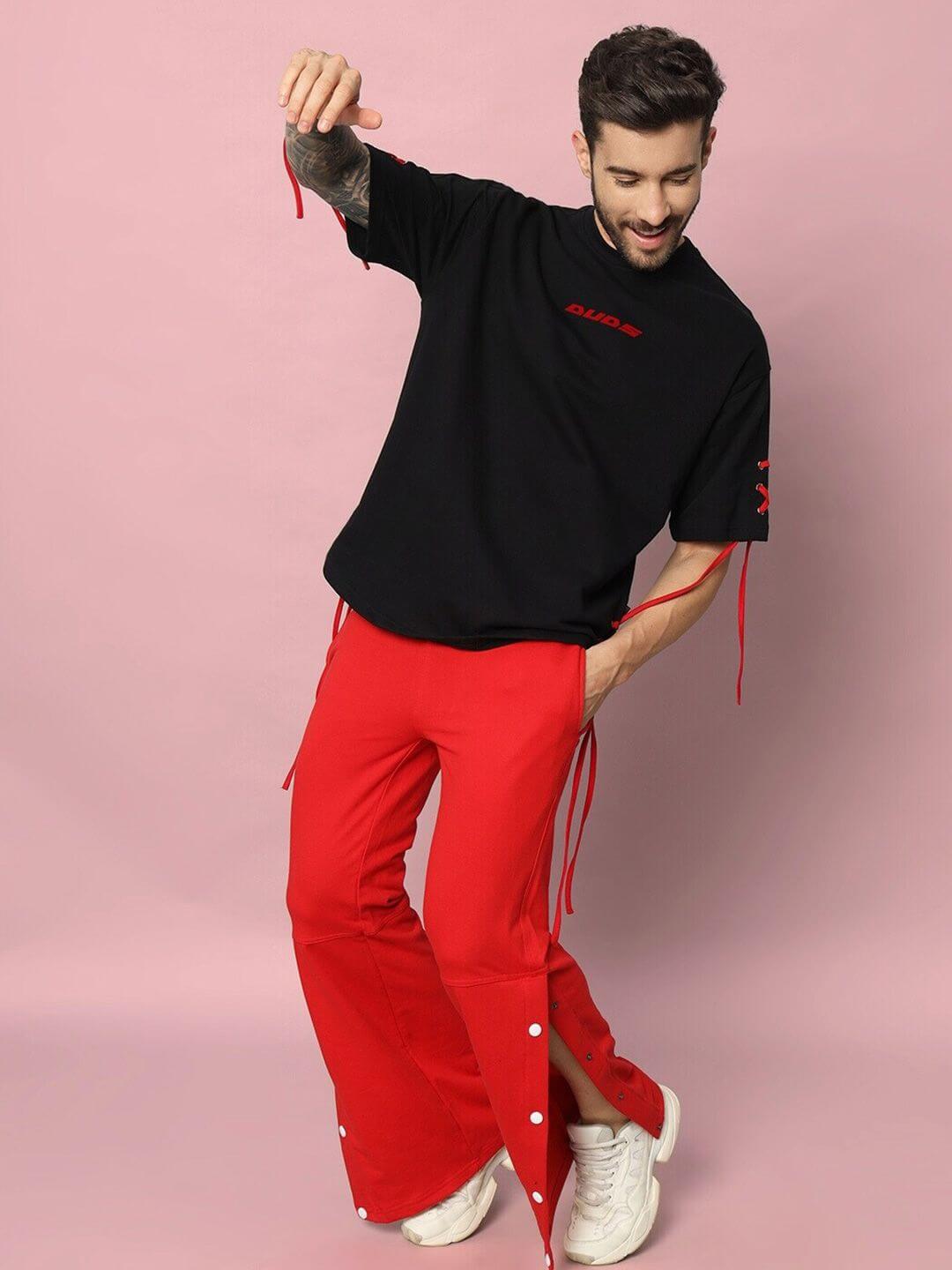 Man wearing the BOWLINE oversized black t-shirt with red pants, showcasing casual style in premium cotton fabric. Made in India.