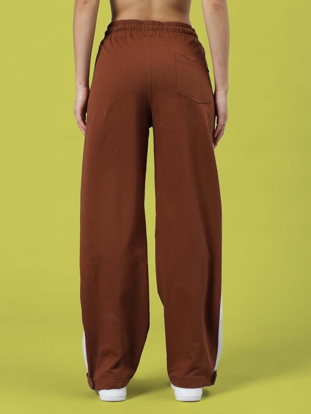Back view of Women's Wonder Slit Zipper Joggers in brown, showcasing elastic waistband and single back pocket against a yellow background.