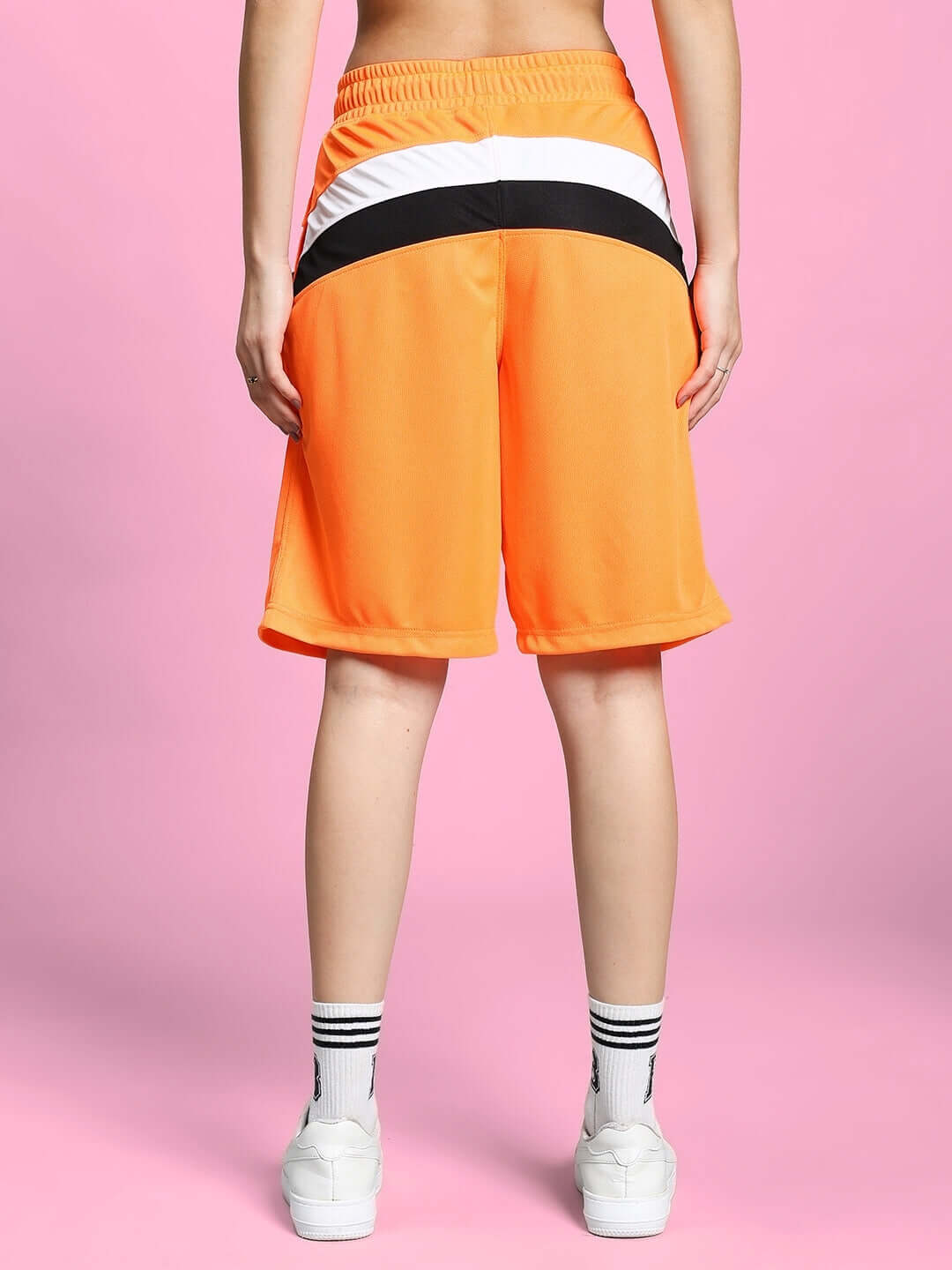 Back view of Women's FIFA Colorblock Co-ord Set in orange, showcasing sports polyester fabric shorts with elastic waistband on pink background.