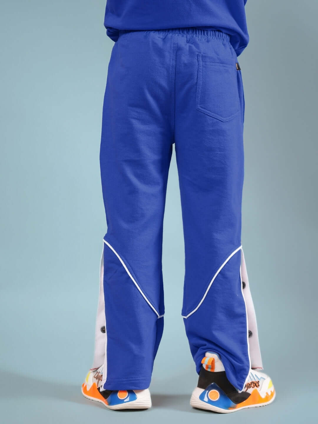 Blue Washington Huskies co-ord pants for kids with white side panels and orange sneakers.