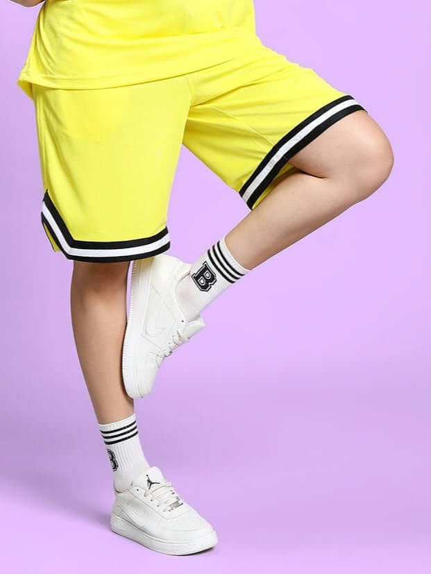 Women's Vigor Regular Fit Yellow Shorts with Black Trim, offers customizable sizing for a perfect fit, shown with white sneakers.