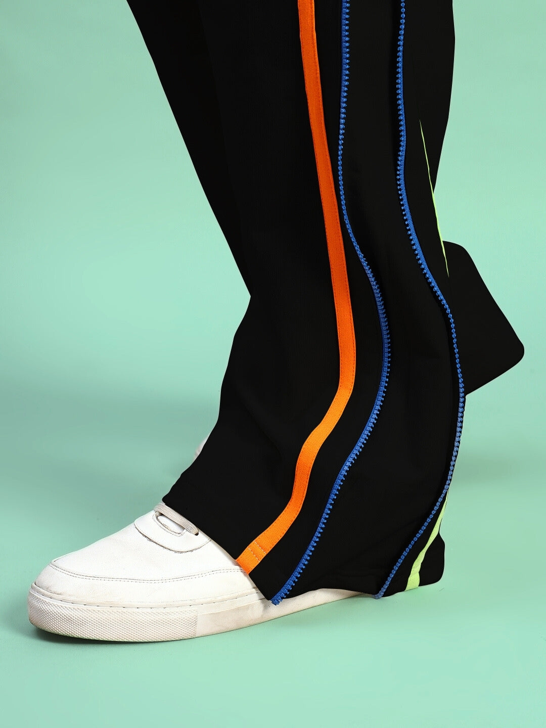 Black joggers with colorful side zippers by DUDS, featuring a white sneaker for a stylish look.